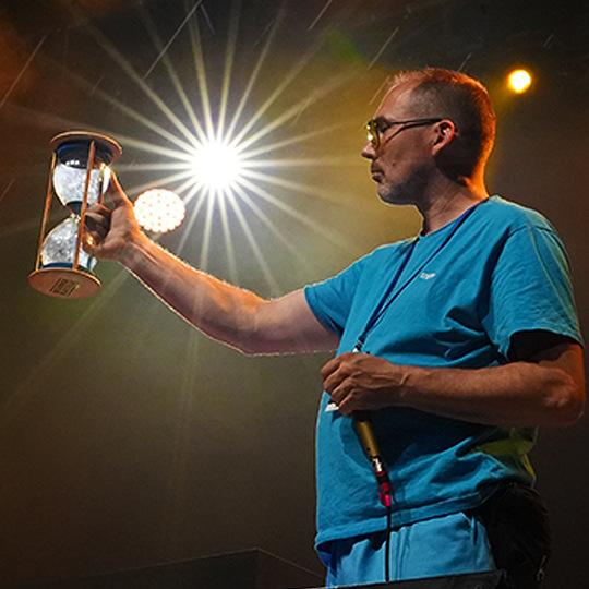 Bee Low the producer of the Beatbox Battle World Championship event series is checking the competition timing with his hour glass under the spotlight at Huxleys neue Welt in Berlin