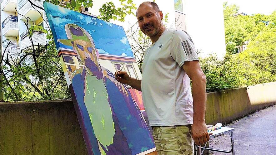 Bee Low the Graffiti Style Writer is painting a self portrait next to a Berlin S-Bahn with a paint brush on a canvas